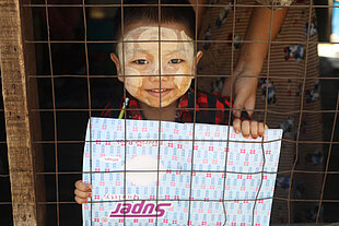 Kleiner Junge in Myanmar zeigt stolz sein neues Schulheft